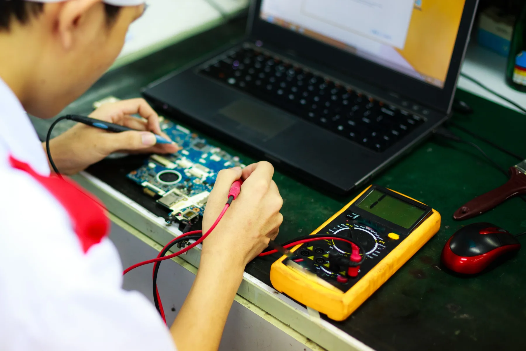 Technician measuring a circuit board with probes and a multimeter