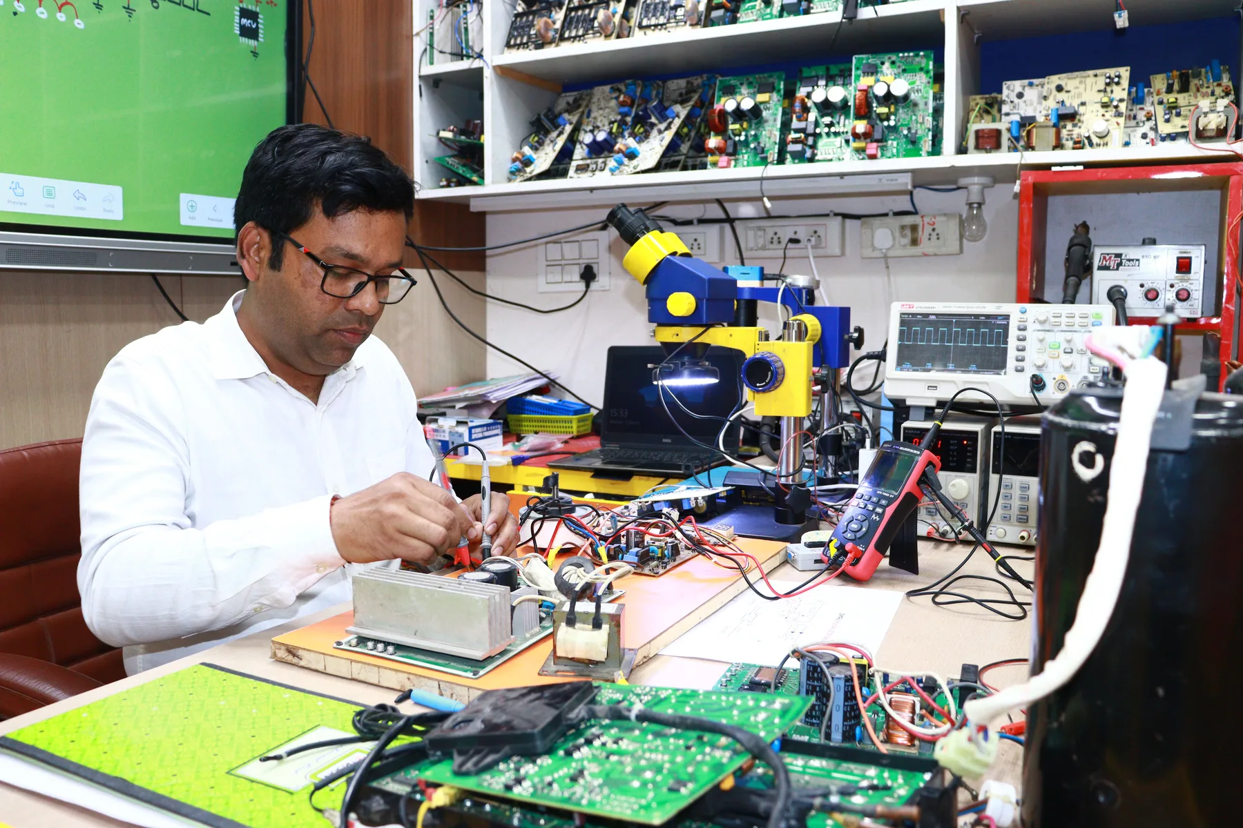 Electronics testing at a workbench with an oscilloscope and microscope