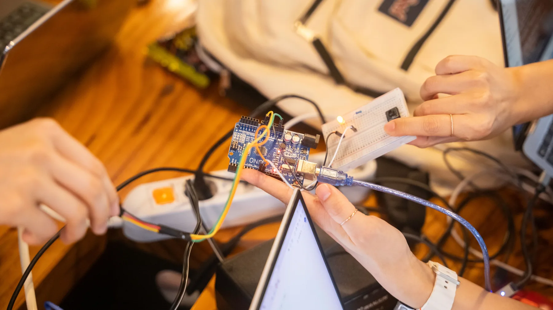 Hands connecting a development board and breadboard prototype