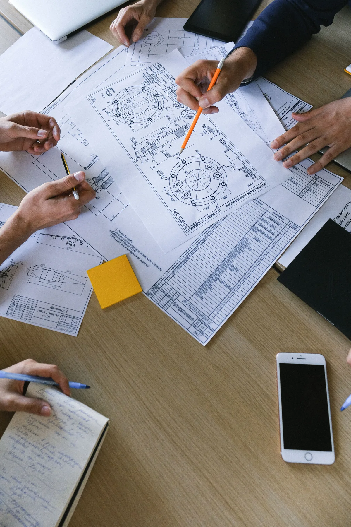 People reviewing technical drawings and recording notes
